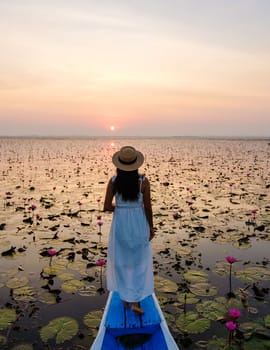 Asian women in a boat at the Beautiful Red Lotus Sea Kumphawapi is full of pink flowers in Udon Thani in northern Thailand. Flora of Southeast Asia.