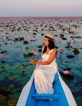 Asian women in a boat at the Beautiful Red Lotus Sea Kumphawapi is full of pink flowers in Udon Thani in northern Thailand. Flora of Southeast Asia.