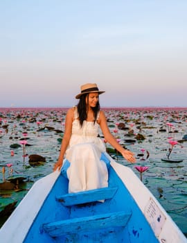 Thai women in a boat at the Beautiful Red Lotus Sea Kumphawapi is full of pink flowers in Udon Thani in northern Thailand. Flora of Southeast Asia.