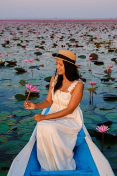 Thai women in a boat at the Beautiful Red Lotus Sea Kumphawapi is full of pink flowers in Udon Thani in northern Thailand. Flora of Southeast Asia.