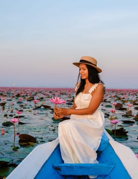 Asian women in a boat at the Beautiful Red Lotus Sea full of pink flowers in Udon Thani in northern Thailand. Flora of Southeast Asia.