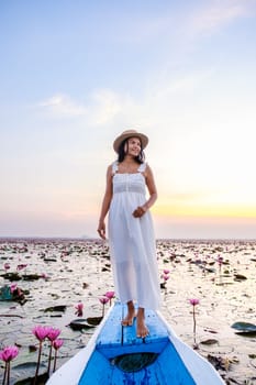 Asian women in a boat at the Beautiful Red Lotus Sea Kumphawapi is full of pink flowers in Udon Thani in Northern Thailand Isaan. Flora of Southeast Asia.