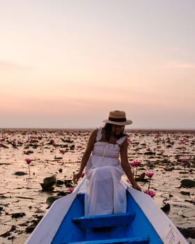 Asian women with a hat and dress in a boat at the Beautiful Red Lotus Sea Kumphawapi is full of pink flowers in Udon Thani in northern Thailand. Flora of Southeast Asia.