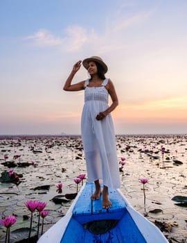 Asian women in a boat at the Beautiful Red Lotus Sea Kumphawapi is full of pink flowers in Udon Thani in Northern Thailand Isaan. Flora of Southeast Asia.