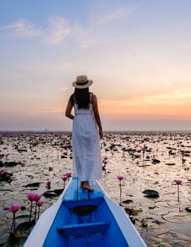 Asian women with a hat and dress in a boat at the Beautiful Red Lotus Sea Kumphawapi is full of pink flowers in Udon Thani in northern Thailand. Flora of Southeast Asia.