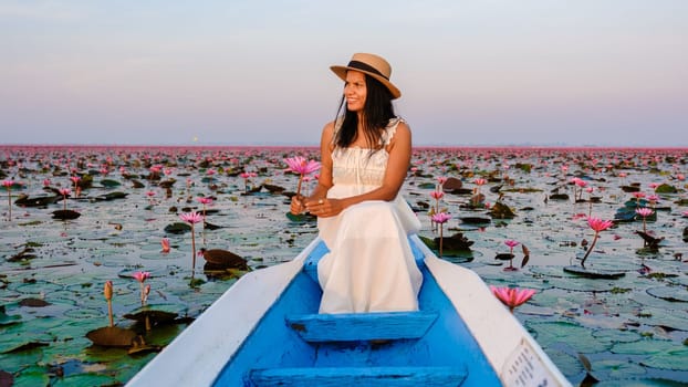 Asian women in a boat at the Beautiful Red Lotus Sea Kumphawapi is full of pink flowers in Udon Thani in northern Thailand. Flora of Southeast Asia.