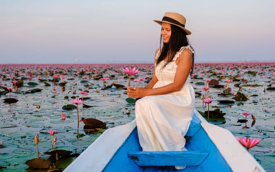 Asian women in a boat at the Beautiful Red Lotus Sea Kumphawapi is full of pink flowers in Udon Thani in Northern Thailand Isaan. Flora of Southeast Asia.