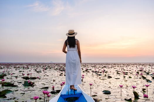 Asian women in a boat at the Beautiful Red Lotus Sea Kumphawapi is full of pink flowers in Udon Thani in northern Thailand. Flora of Southeast Asia.