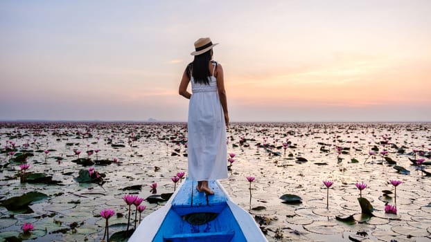 Asian women in a boat at the Beautiful Red Lotus Sea Kumphawapi is full of pink flowers in Udon Thani in Northern Thailand Isaan. Flora of Southeast Asia.