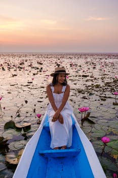 Asian women in a boat at the Beautiful Red Lotus Sea Kumphawapi is full of pink flowers in Udon Thani in northern Thailand. Flora of Southeast Asia.