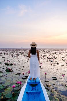 Asian women in a boat at the Beautiful Red Lotus Sea full of pink flowers in Udon Thani in northern Thailand. Flora of Southeast Asia.