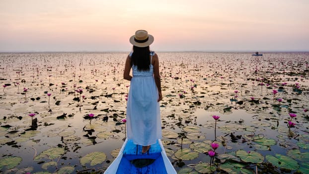 Asian women in a boat at the Beautiful Red Lotus Sea Kumphawapi is full of pink flowers in Udon Thani in northern Thailand. Flora of Southeast Asia.