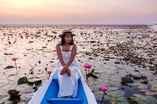 Asian women with a hat and dress in a boat at the Beautiful Red Lotus Sea Kumphawapi is full of pink flowers in Udon Thani in northern Thailand. Flora of Southeast Asia.