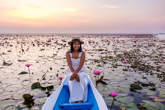 Asian women in a boat at the Beautiful Red Lotus Sea Kumphawapi is full of pink flowers in Udon Thani in northern Thailand. Flora of Southeast Asia.