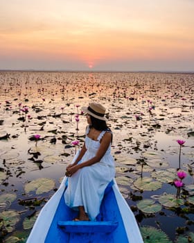 Thai women in a boat at the Beautiful Red Lotus Sea Kumphawapi is full of pink flowers in Udon Thani in northern Thailand. Flora of Southeast Asia.