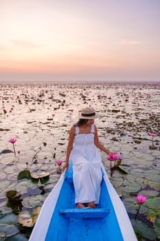 Asian women in a boat at the Beautiful Red Lotus Sea Kumphawapi is full of pink flowers in Udon Thani in northern Thailand. Flora of Southeast Asia.