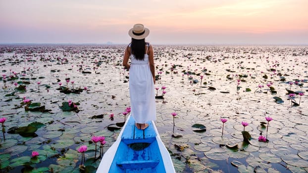 Asian women in a boat at the Beautiful Red Lotus Sea full of pink flowers in Udon Thani in northern Thailand. Flora of Southeast Asia.