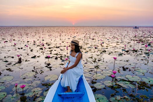 Thai women in a boat at the Beautiful Red Lotus Sea Kumphawapi is full of pink flowers in Udon Thani in northern Thailand. Flora of Southeast Asia.