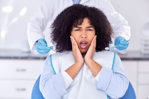 .a young woman experiencing pain and anxiety while having a dental procedure performed on her