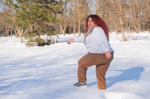 A fat red-haired woman in a white sweatshirt walks through snowdrifts