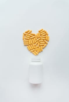 Yellow pills in the shape of a heart, health and heart problems along with a plastic jar. The concept of medicine and healthcare. Place for an inscription, vertical photo