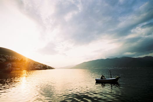 Man and woman kiss in a boat in the sea against the backdrop of mountains. High quality photo