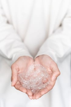 A woman's hand holds invisible aligners on a white background of her sweater, close-up. Girl in full growth holds a handful of aligners in her palms.