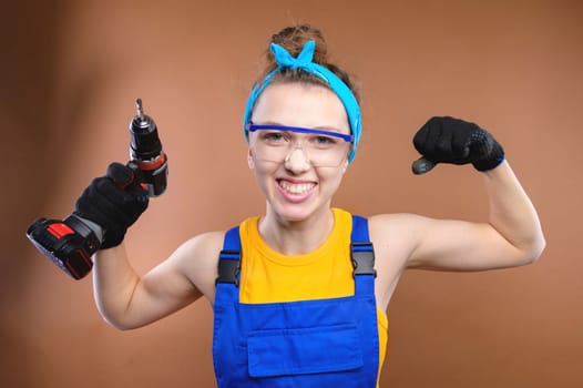 Smiling young caucasian woman in goggles with a screwdriver in her hands and in uniform stands in the studio.
