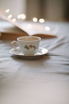 Spring still life. Breakfast in bed. White bedroom. Sweet home. Book and coffee cup