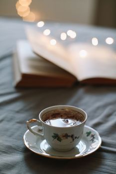 Light cozy bedroom, Coffee or tea cup and an open book on the bed. Spring still life. Breakfast in bed.