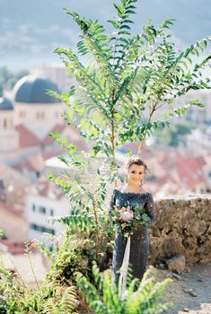 Bride in a blue lace dress stands on the observation deck above the ancient town. High quality photo