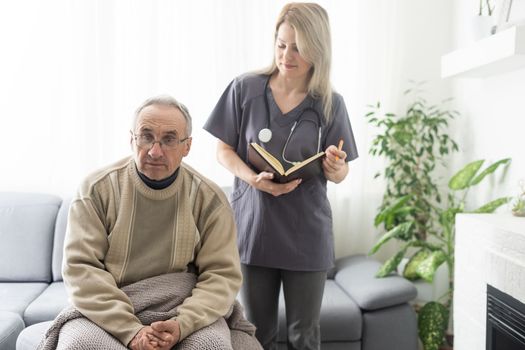 Caring nurse talks to old patient holds his hand sit in living room at homecare visit provide psychological support listen complains showing empathy encouraging. Geriatrics medicine caregiving concept.