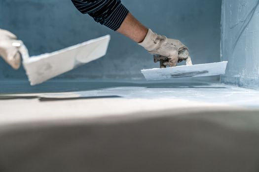 work with trowel on floor and wall in new room in building. High quality photo