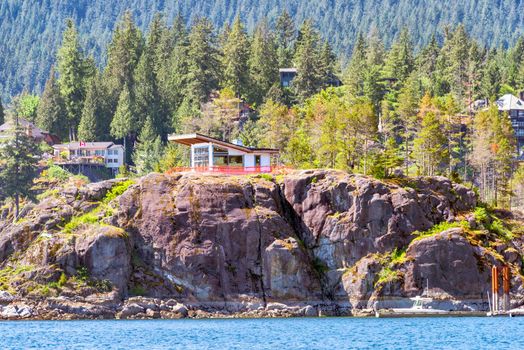 Rocky shore of the Pacific ocean in Vancouver. Residential house under contstruction at the waterfront