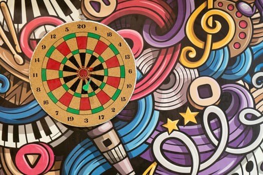 Dart board with bulls eye placed on a wall with painted design showing a new age cafe, library game room India