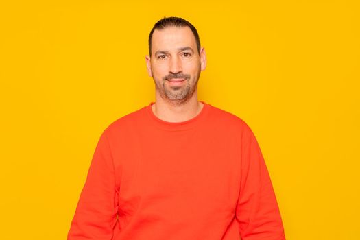 Isolated photo of a handsome man with a beard, wears a casual red sweater. He has a cheerful and relaxed expression, he is happy and content with his life.