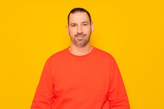 Isolated photo of a handsome man with a beard, wears a casual red sweater. He has a cheerful and relaxed expression, he is happy and content with his life.