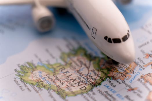 Close up of colorful map with miniature passenger plane highlighting Ireland through selective focus, shallow depth of field, background blur. High quality photo