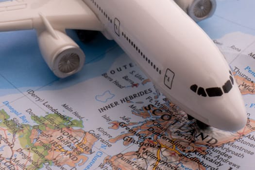 Close up of colorful map with miniature passenger plane highlighting Glasgow, Scotland through selective focus, shallow depth of field, background blur. High quality photo