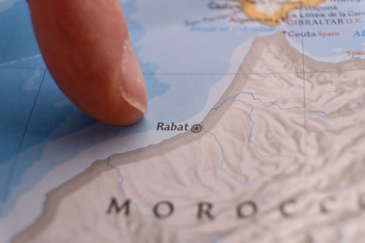 Finger pointing to Rabat, Morocco on colorful map with selective focus, shallow depth of field, background blur. High quality photo