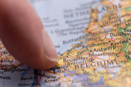 Finger pointing to Brussels, Belgium on colorful map with selective focus, shallow depth of field, background blur. High quality photo