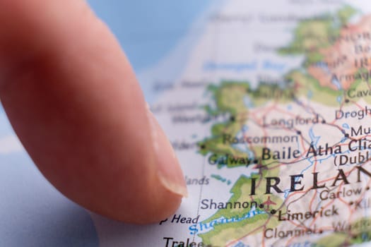 Finger pointing to Shannon, Ireland on colorful map with selective focus, shallow depth of field, background blur. High quality photo