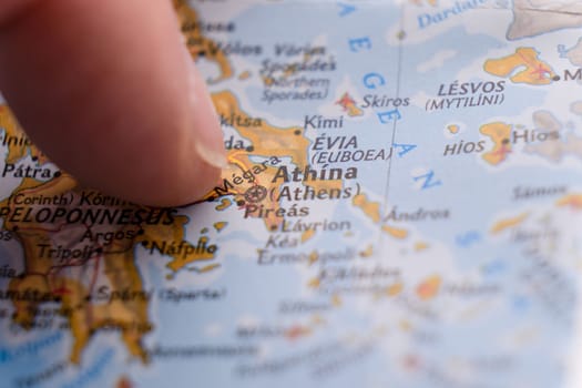 Close up of finger pointing to Athens, Greece on colorful map, background blur. High quality photo