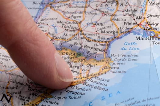 Finger pointing to Barcelona, Spain on a map with selective focus, background blur. High quality photo