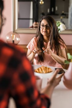 Young diverse loving couple eating croissant and talks together at home in breakfast time. Communication and relationship