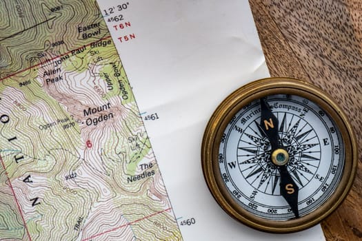 Close up of wooden table with topographical map, compass placed on top. High quality photo