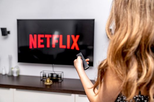 Olomouc, Czech Republic - February 10, 2023: teenager turned on netflix on tv with remote control. High quality photo