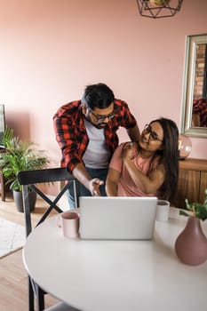 technology, remote job and lifestyle concept - happy indian man in glasses with laptop computer working at home office