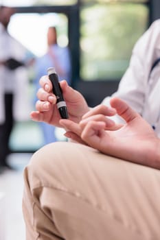 Senior physician measuring insulin level and glucose in blood sample using glucometer during examination with asian patient with diabetes. Doctor doing medical test in hospital reception. Close up