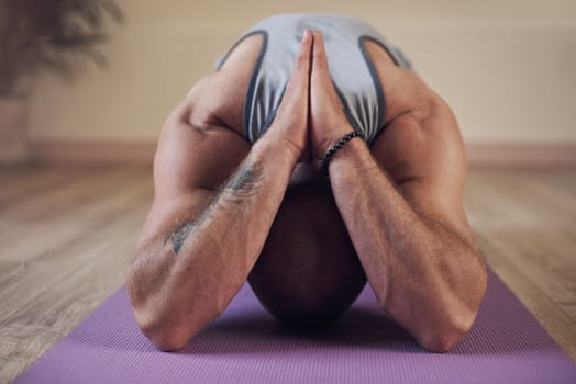 Yoga is a practice that runs deep in the muscles. an unrecognizable man holding an extended childs pose during an indoor yoga session alone